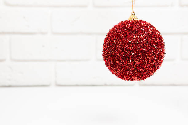 白いレンガの壁の背景に新年、クリスマスの装飾、赤い光沢のあるボール