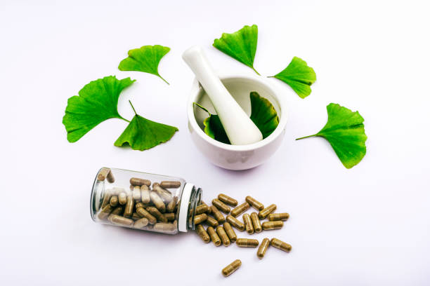 Pills and fresh green ginkgo biloba leaves, mortar and pestle on white background. Natural herbal medicine concept. Top view Pills and fresh green ginkgo biloba leaves, mortar and pestle on white background. Natural herbal medicine concept. Top view. brain jar stock pictures, royalty-free photos & images