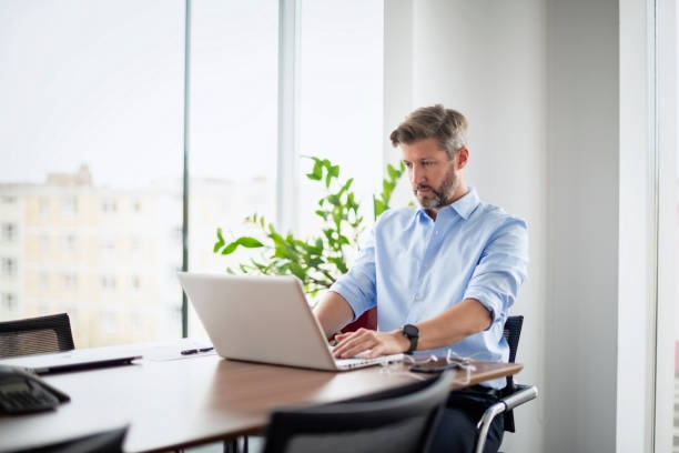 istock Middle aged businessman using laptop at the office 1447399798