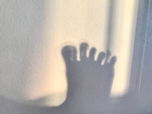 Sunlight shadow effects by of a dancing feet on the bedroom wall during the sunset