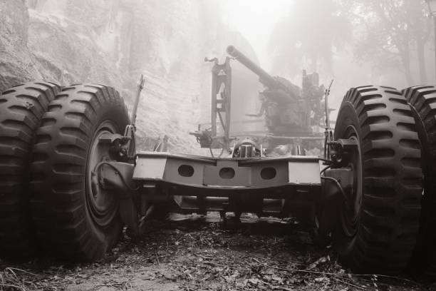 An artillery cannon from WW2 in the fog with a wheeled carriage in foreground