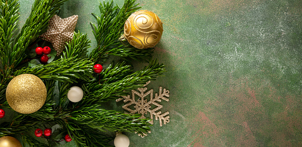 Christmas banner with fir branches, decorations, baubles and candy canes on green textured background.