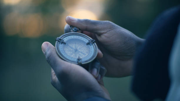African ethnicity person holding a compass. Planning trip and checking directions stock photo