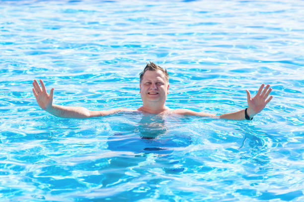 istock Young blond man swims in the pool with children 1447403677