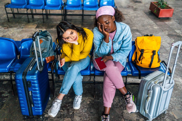 Women with suitcases sitting bored at railway station stock photo