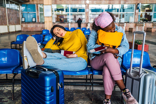 Young multi ethnic women traveler friends sleeping at railway station