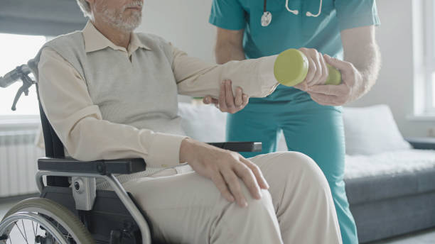 istock Man with disability doing exercise with assistance of physical therapist, mobility impairment 1447407228