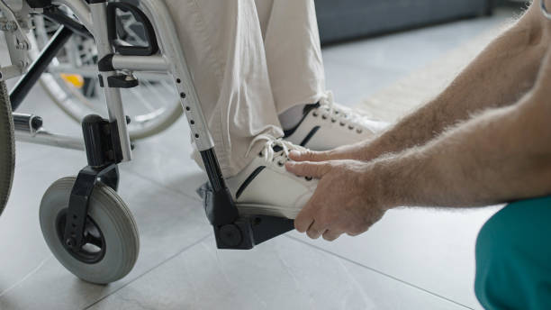опекун завязывает шнурки пациента, ухаживает за пенсионером с инвалидностью в доме престарелых - senior adult shoelace human leg leg стоковые фото и изображения