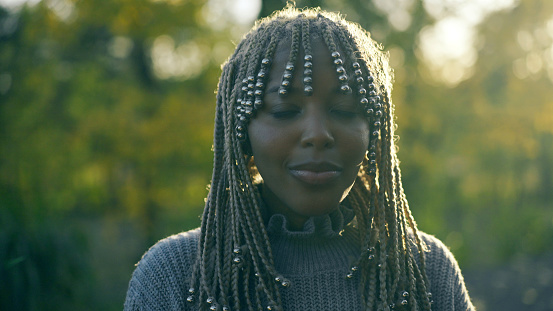 Beautiful african ethnicity girl with cornrow braids posing for the camera in the park.