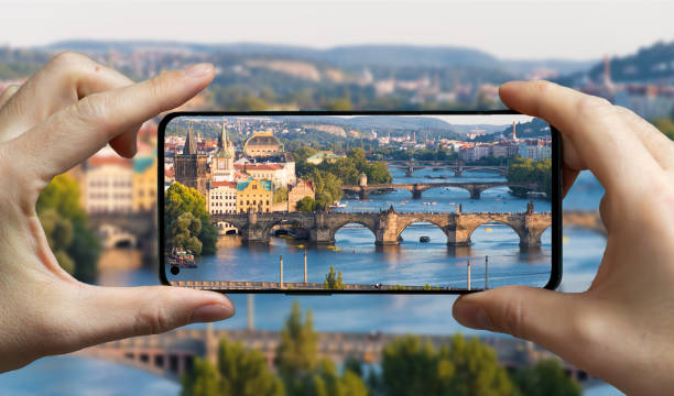 tourist taking a picture with a mobile phone of prague, czech republic. - ponte charles imagens e fotografias de stock