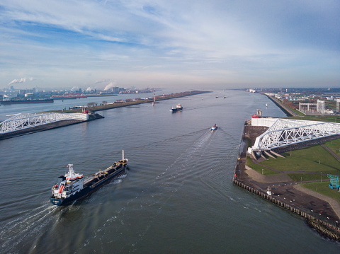 Rotterdam, Netherlands - December 22, 2021: aerial view of a ship passing the Maeslant Storm Surge Barrier that protects Rotterdam and many other towns around it from flooding during a storm on the North Sea