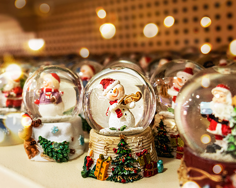 snow globes with snowman and santa claus on a store shelf ,snow globes on a store shelf or at a Christmas fair.