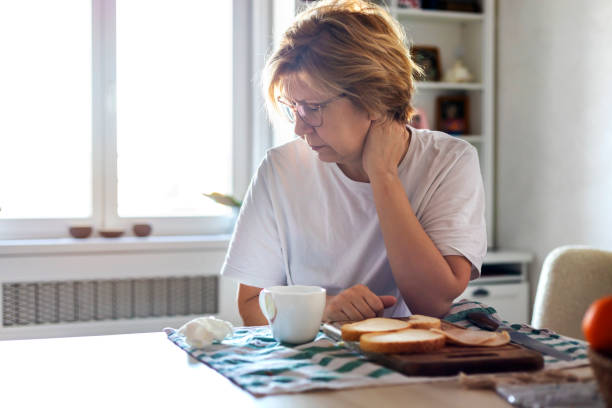 mature woman suffering from pain in her arms and headache - eating sandwich emotional stress food imagens e fotografias de stock