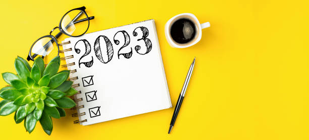 istock New year resolutions 2023 on desk. 2023 resolutions list with notebook, coffee cup on yellow table. Goals, resolutions, plan, action, checklist concept. New Year 2023 template 1447413218