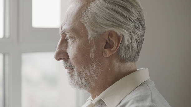 istock Close-up of mature gray-haired man looking out the window, thinking about problems 1447417115