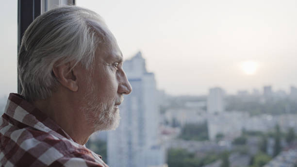 istock Pensive old man looking out the window at morning cityscape, retirement security 1447417201