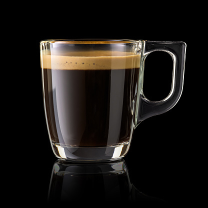 Full cup of espresso coffee isolated on black background.