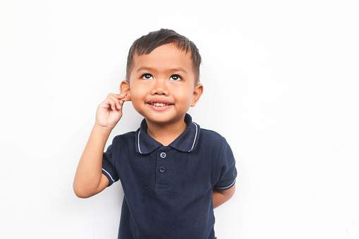 Toddler boy smiling while pulling the ear