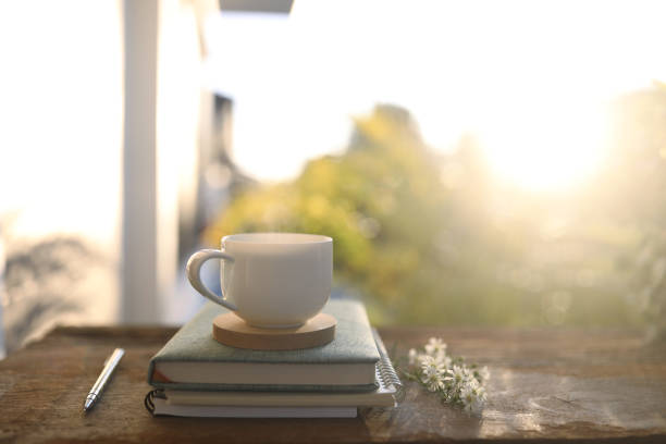 istock white coffee cup and notebook on wooden table with natural sunlight 1447425766