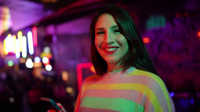 Portrait of a young transgender woman using smartphone at nightclub