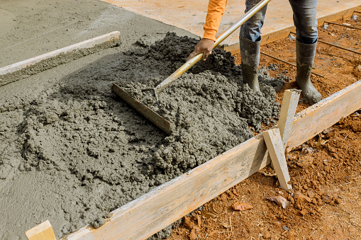 Los trabajadores vierten cemento para crear una acera adicional que será construida en el costado de la casa por un equipo de construcción photo