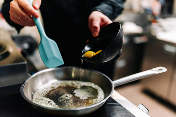 istock man chef cooking tasty scrambled eggs in frying pan on kitchen 1447430822
