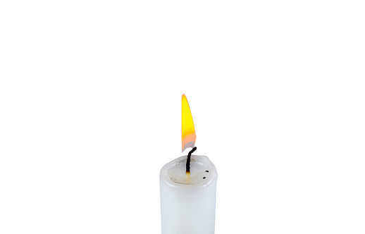 Burning white candle isolated on the white background. Close up photo.