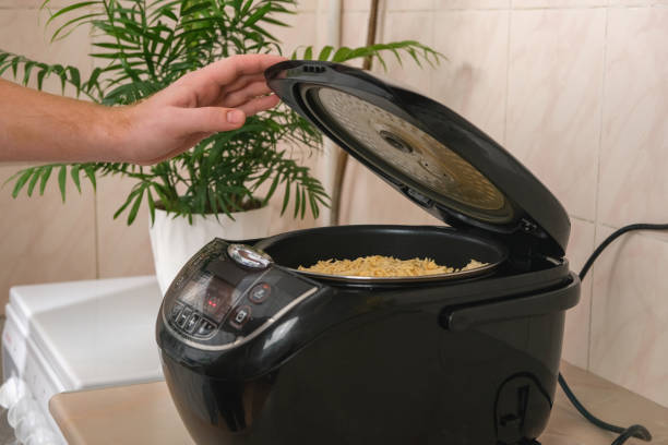 istock Man closes lid of slow cooker and selects cooking program, temperature, time. multicooker. Cooking lunch dinner for family home. Process of cooking meat in French with potatoes, tomatoes, cheese. 1447433735