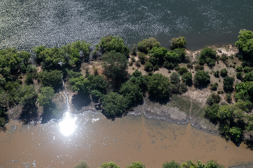 Aerial shot of the upper Sambezi river, showing a herd of elephants on the bank of the river.