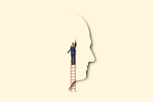 A woman climbs a ladder as she attempts to reach into someone's mind.