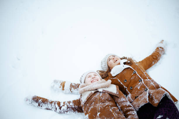 istock smiling modern mother and child making snow angel 1447438966