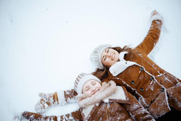 istock smiling modern mother and daughter making snow angel 1447438967