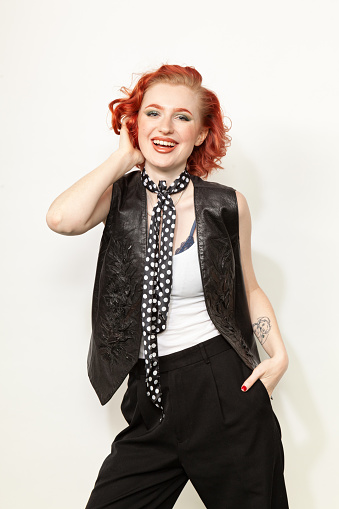 Studio portrait of a young red-haired white woman dressed in retro style against a white background