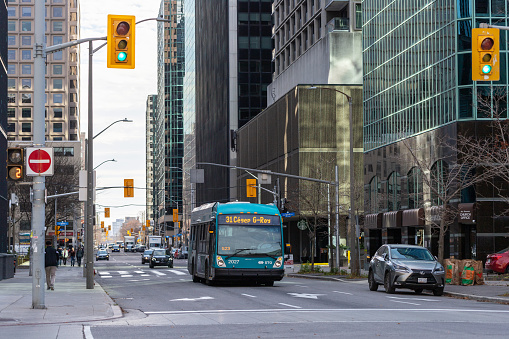 Ottawa, Canada - November 10, 2022: Public bus on road in downtown. Cityscape with busy traffic and public transportation. Street with crossroads and traffic lights.