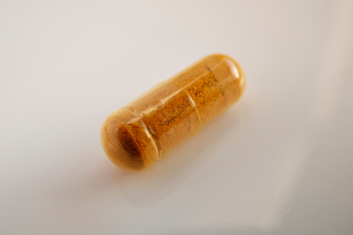 Close up of an organic Turmeric capsule with black pepper.