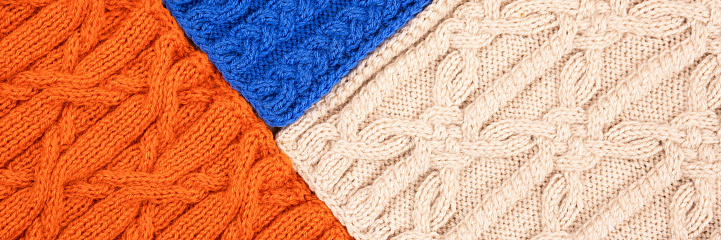 Knitted blue orange and beige background. Large knitted fabric with a pattern. Close-up of a knitted blanket. Banner