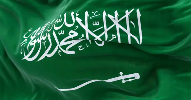 Close-up view of Saudi Arabia national flag waving in the wind. The Kingdom of Saudi Arabia is a country in Western Asia. Fabric textured background. Selective focus. Realistic 3d illustration