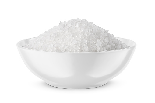 Coarse sea salt in white bowl isolated on white background. Front view.