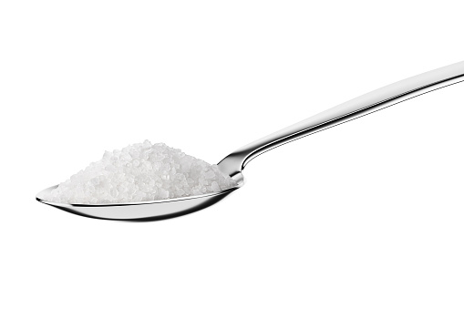 Teaspoon with rock coarse salt isolated on white background.