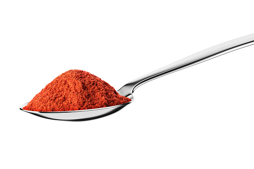 Teaspoon with ground red pepper isolated on white background.