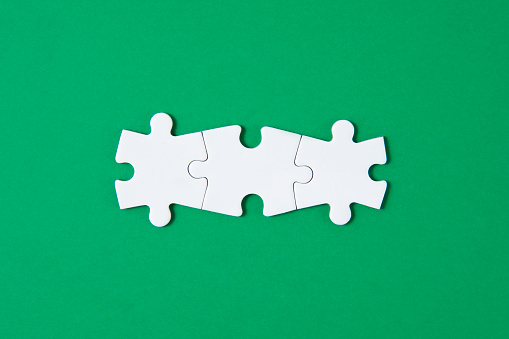 White puzzle pieces comes together on green background