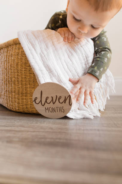 An 11-Month-Old Christmas Baby Boy Dressed in a Dark Green Thermal Onesie with Little Christmas Trees on it While in a Seagrass Moses Basket on the Floor at Home in December 2022 An 11-Month-Old Christmas Baby Boy Dressed in a Dark Green Thermal Onesie with Little Christmas Trees on it While in a Seagrass Moses Basket on the Floor at Home in December 2022 moses basket stock pictures, royalty-free photos & images