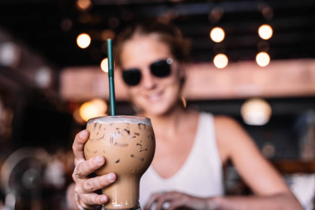 Focus on a glass of frappe held by a woman in a cafeteria stock photo