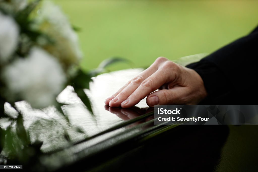 Closeup of womans hand on coffin Closeup of womans hand on coffin saying goodbye at outdoor funeral ceremony, copy space Funeral Stock Photo