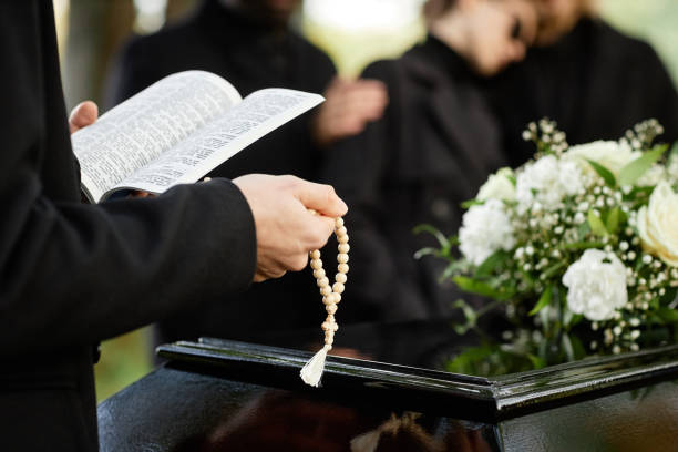 Close up of person in black praying at outdoor funeral Close up of person in black praying at outdoor funeral and holding Bible with rosary, copy space Funeral stock pictures, royalty-free photos & images
