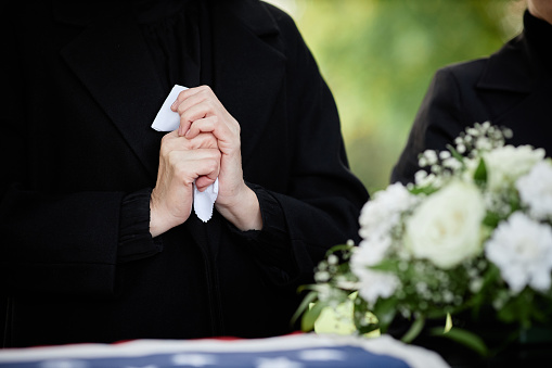 This military honor guard carefully folds the United States flag for presentation to family members at a veteran's funeral. Selective focus on flag and gloved hands. Would make good illustration for U.S. Veteran's Day, U.S. Memorial Day or honoring military service.