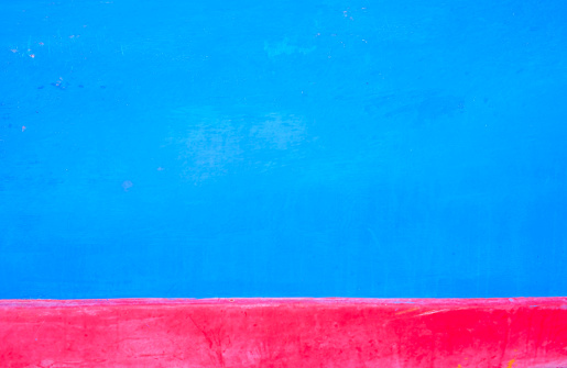 horizontal detail of a  wooden boat hull red brightly painted in red and blue under the day light, on Sainte Marie beach