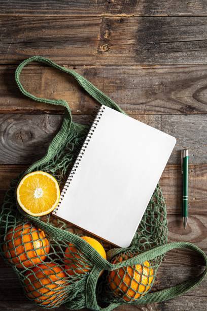 istock Oranges in a string bag and blank notepad, eco-friendly product on a wooden background. 1447474353