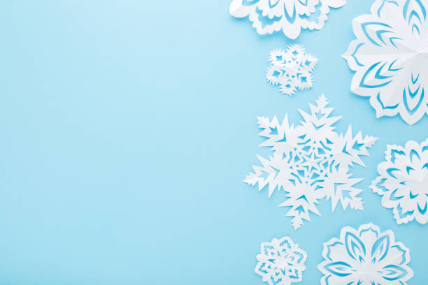 istock Different white snowflake shapes created from paper on light blue table background. Pastel color. Closeup. Top down view. Handmade decoration elements for winter festive. Empty place for text. 1447475725
