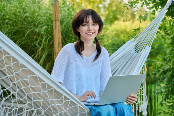 istock Teenage girl relaxing in hammock using laptop for leisure study 1447476457